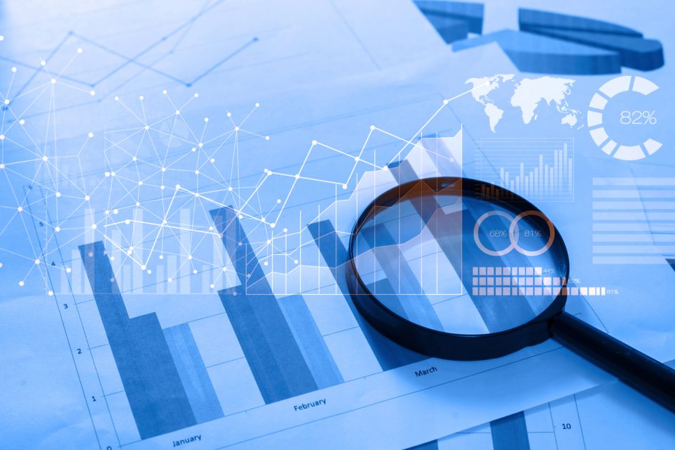 Magnifying glass over printed financial charts and market data